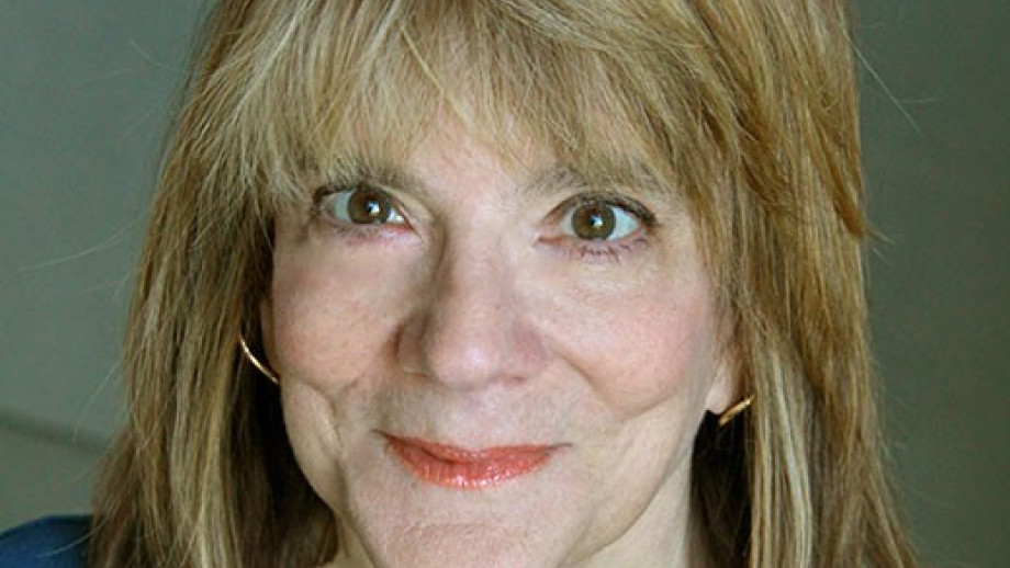 Portrait of a smiling middle-aged woman with blonde hair and green eyes.