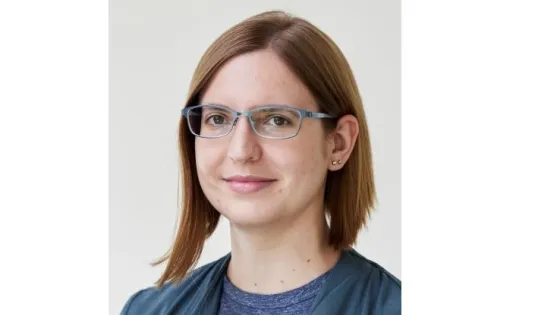 A woman with short brown hair and glasses smiling at the camera.