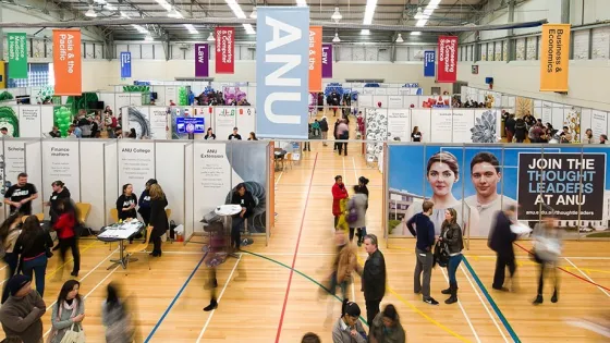 An indoor exhibition at a university with various informational booths and people walking around.