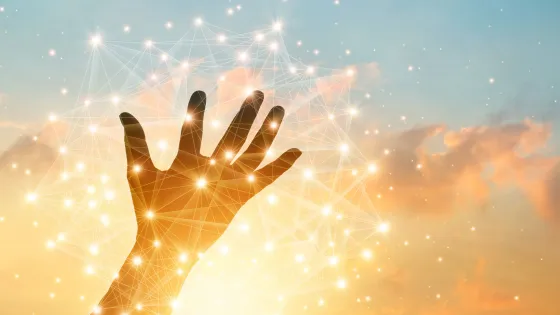 A human hand reaching towards a digital network overlay against a sky with clouds at sunset.