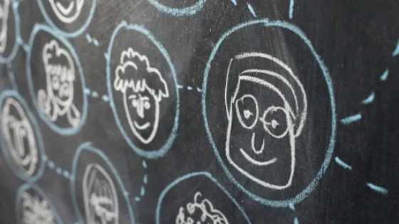 Chalk drawings of various smiling faces on a blackboard.