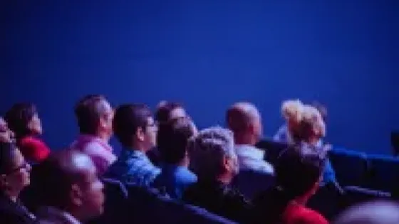 Crowd seated in theatre style seating looking towards presenter