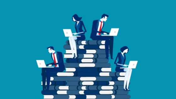 Illustration of five business professionals using laptops while sitting on a stacked pile of large books, symbolizing a hierarchy or progression.