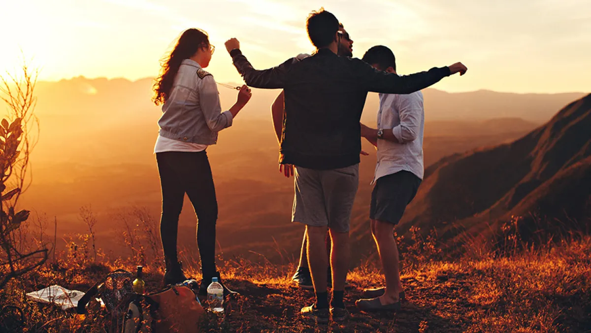Friends standing on top of mountain at dusk