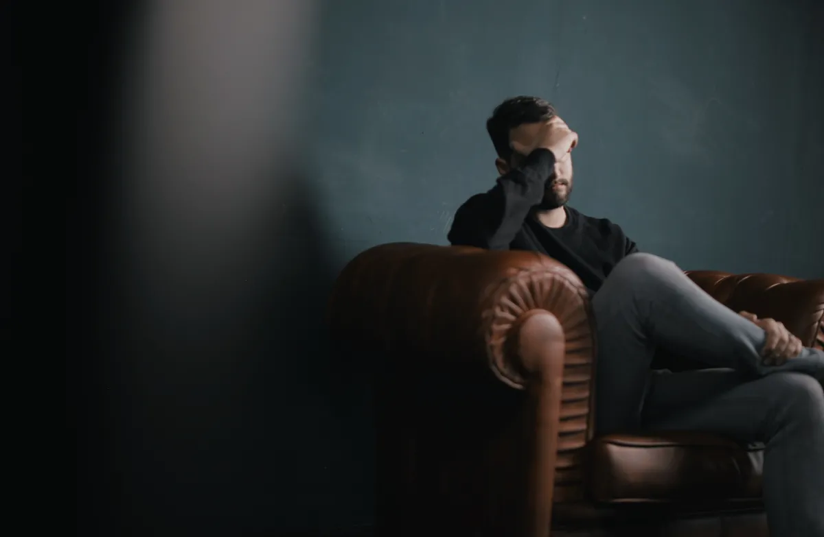 Man sitting with head in hand expressing guilt