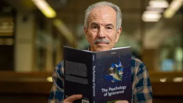Professor Michael Smithson is reading a book titled The Psychology of Ignorance