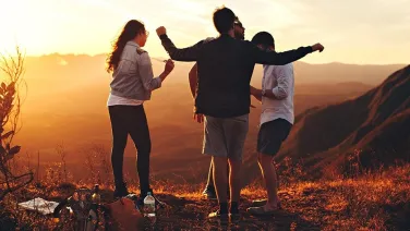 A group of people standing on a hill, looking care free and happy.